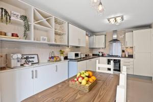 a kitchen with white cabinets and a basket of fruit on a table at Radiant Retreat Ideal for LegoLand, Windsor, & LHR in Slough