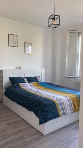 - une chambre blanche avec un lit et une couette colorée dans l'établissement Chambre double 10 min du circuit, à Allonnes