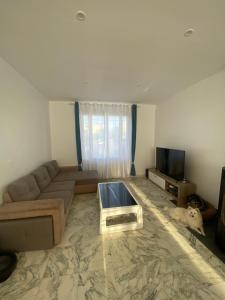 un salon avec un canapé et une télévision dans l'établissement Chambre double 10 min du circuit, à Allonnes