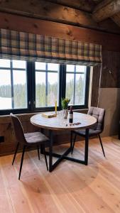 una mesa y sillas en una habitación con ventanas en Liaplassen Mountain Chalet - Beitostølen, en Beitostølen
