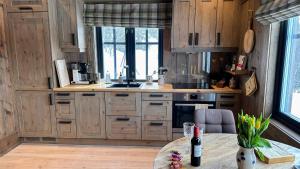 a kitchen with wooden cabinets and a table with a bottle of wine at Liaplassen Mountain Chalet - Beitostølen in Beitostøl