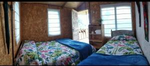 a bedroom with two beds and two windows at Casa de leña, cabaña rural in Villa de Leyva