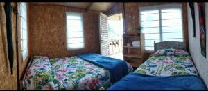 a bedroom with two beds and two windows at Casa de Leña - Cabaña Rural in Villa de Leyva