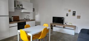 a small kitchen with a white table and yellow chairs at Residenza il Filo in Orosei