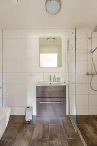 ein Badezimmer mit einem Waschbecken, einer Badewanne und einem Spiegel in der Unterkunft Woonboerderij Dijkerhoek in Holten