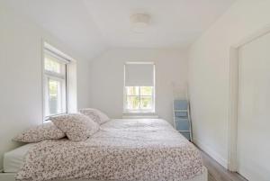 ein weißes Schlafzimmer mit einem Bett und zwei Fenstern in der Unterkunft Woonboerderij Dijkerhoek in Holten