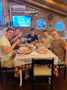 un grupo de personas sentadas alrededor de una mesa comiendo pizza en Hotel Arsenal en Ksamil