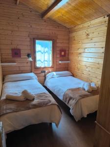 a bedroom with two beds in a log cabin at Cabañas Miraduero in Aldeadávila de la Ribera
