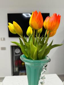 un vaso verde con fiori arancioni e gialli di Varese Apartment a Varese