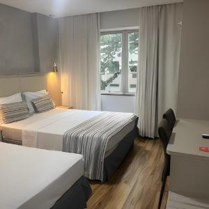a hotel room with two beds and a window at Real Palace Hotel in Rio de Janeiro