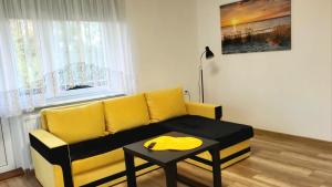 a living room with a yellow couch and a table at Dom na Błękitnej in Karwieńskie Błoto Pierwsze