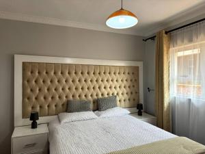 a bedroom with a large bed with a large padded headboard at Nid De Chateau in Harare +23 photos