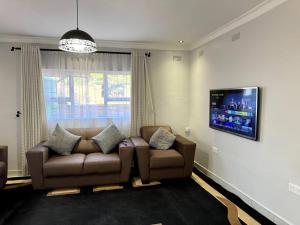 a living room with a couch and a flat screen tv at Nid De Chateau in Harare