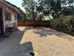 a brick courtyard with a tree and a building at Nid De Chateau in Harare