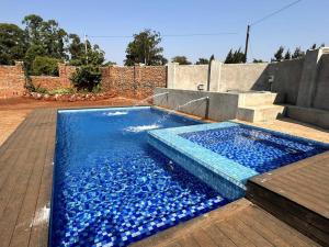a swimming pool filled with blue water next to a brick wall at Nid De Chateau in Harare