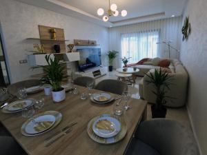 a living room with a wooden table with plates and wine glasses at Appartement charmant au parc de Mohammedia, à seulement 2 pas de la plage in Mohammedia