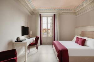 una camera d'albergo con letto, scrivania e finestra di Prato dei Miracoli Residenza d'Epoca a Pisa