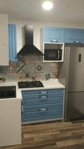 a kitchen with blue cabinets and a stainless steel refrigerator at Holiday house Stela in Gdinj +24 photos