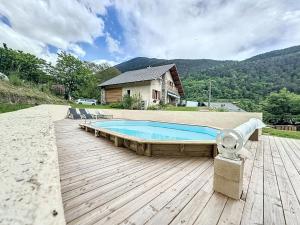 a swimming pool on a wooden deck next to a house at CHALET DON PAPA in Saint-Martin-Vésubie