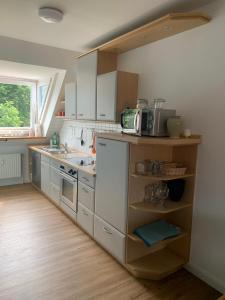 una cucina con armadi bianchi, lavandino e finestra di "de hyggelige Loftrum" a Eckernförde