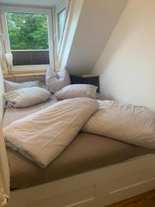 ein Bett mit Kissen darauf in einem Zimmer mit Fenster in der Unterkunft "de hyggelige Loftrum" in Eckernförde
