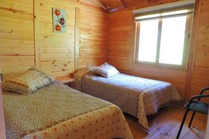 a bedroom with two beds in a wooden cabin at Cabaña Caracolí. Tranquilidad vía a la laguna in Ubaque