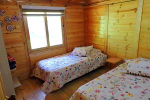 a bedroom with two beds in a log cabin at Cabaña Caracolí. Tranquilidad vía a la laguna in Ubaque