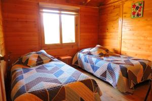 a bedroom with two beds in a log cabin at Cabaña Caracolí. Tranquilidad vía a la laguna in Ubaque