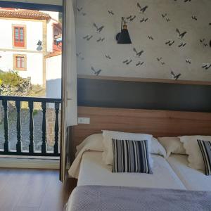 um quarto com duas camas e pássaros na parede em Hotel El Pescador em Tazones