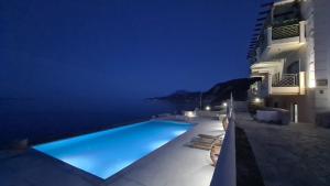 a swimming pool with a view of the ocean at night at Villa Serafeim in Kymi
