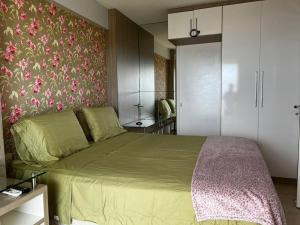 a bedroom with a green bed with a floral wallpaper at Apartamento aconchegante de frente para a praia in Fortaleza +3 photos