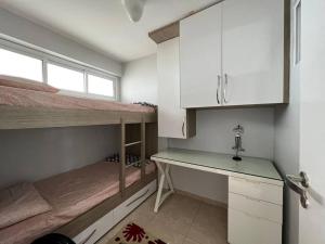a room with two bunk beds and a desk at Apartamento aconchegante de frente para a praia in Fortaleza