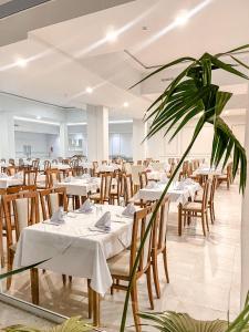 um restaurante com mesas e cadeiras brancas e uma planta em Hammamet Serail em Hammamet