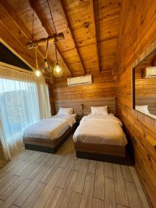 two beds in a room with wooden walls at اكواخ السمو الريفيه in Khalij Salman