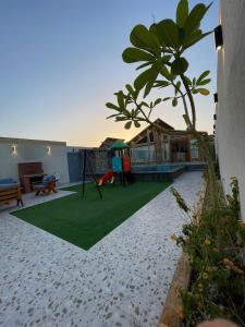 a backyard with a swing and a playground at اكواخ السمو الريفيه in Khalij Salman