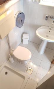 a white bathroom with a toilet and a sink at Apartments Glavinović - Near Beach and Center, Free Parking in Povlja +25 photos