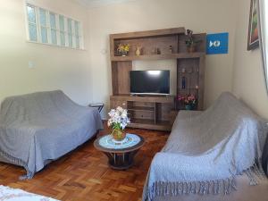 a living room with two beds and a flat screen tv at Apto no Centro de Petrópolis in Petrópolis