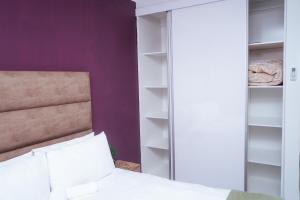 sypialnia z łóżkiem i fioletową ścianą w obiekcie Pristine Guest Apartments w mieście Mthatha