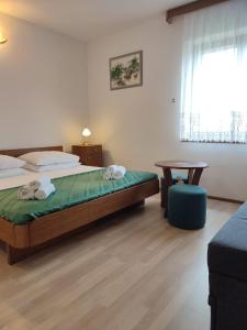 a bedroom with a bed and a table and a window at Apartments Glavinović - Near Beach and Center, Free Parking in Povlja