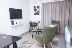 Zimmer mit 2 Stühlen, einem Tisch und einem Bett in der Unterkunft Pristine Guest Apartments in Mthatha