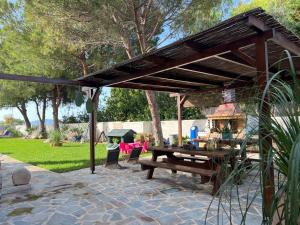 a wooden pavilion with a picnic table in a park at Pampas Seafront villa, 6 bedrooms, North Evvoia in Kanatádhika