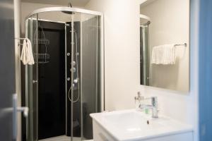 ein Bad mit einer Dusche, einem Waschbecken und einem Spiegel in der Unterkunft Villa Vichéia - Appartement 31 in Vichy