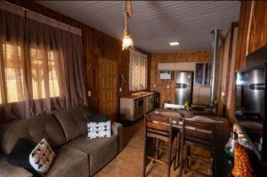 a living room with a couch and a kitchen at Pousada Recanto da Paz in Urupema