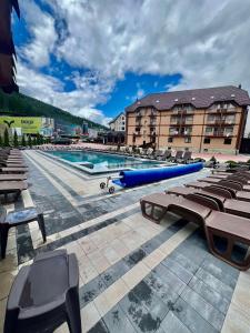 a large swimming pool with benches and a blue raft at Villa Victoria in Bukovel