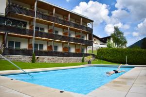 a person swimming in a swimming pool in front of a building at Kreativ Hotel Landhaus Schweigl in Ultimo