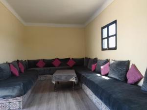 a living room with a black couch with pink pillows at Maison avec piscine pour famille au région de safi in Safi