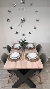 a wooden table with chairs and a clock on the wall at Lux Apartment Nea Kallikratia in Nea Kalikratia