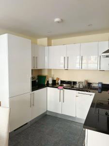 eine Küche mit weißen Schränken und schwarzen Arbeitsplatten in der Unterkunft Convenient 2 BDR 2BA Flat in Central London in London