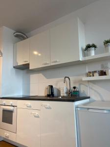 a white kitchen with white cabinets and a sink at Apartament Modlińska in Warsaw