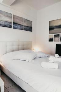 a white bed in a bedroom with pictures on the wall at Gk Suites-Constantin view , auto check-in 24h in Larisa